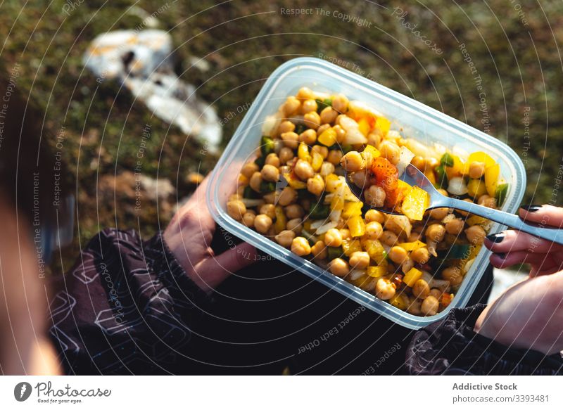 Traveler eating homemade salad while resting in nature woman lunch hike travel tourism break camp container food trekking campsite mix picnic vegetable bowl