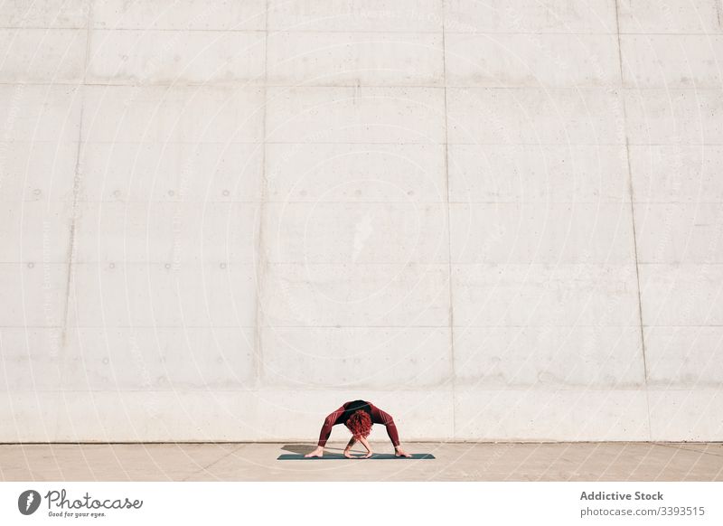 Woman doing wide legged forward bend yoga pose on street woman stretch practice asana training exercise flexible athlete calm gymnastic concrete urban wellness