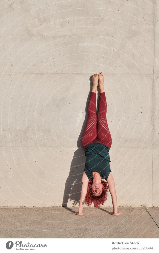 Woman performing handstand while practicing yoga on street woman exercise acrobatic practice balance training urban athlete barefoot concrete healthy