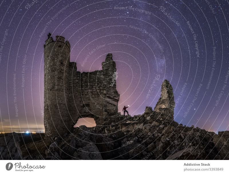 Faceless traveler hiking ruins of castle at night tourist explore ruined lantern sightseeing milky way starry remain old ancient abandoned architecture medieval