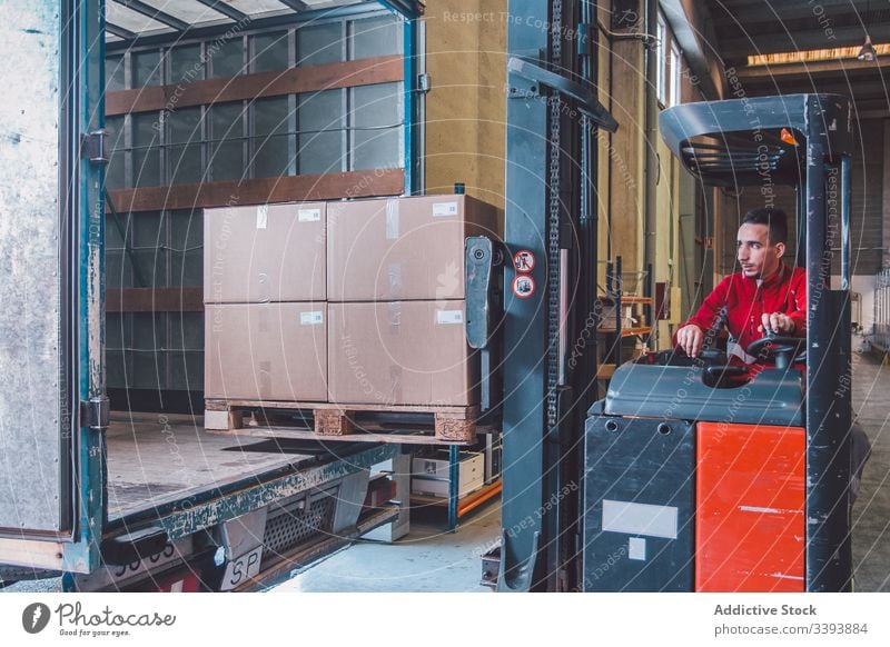 Male worker of logistic company in forklift truck man driver shipment car storage warehouse machine equipment modern operator male service production cargo