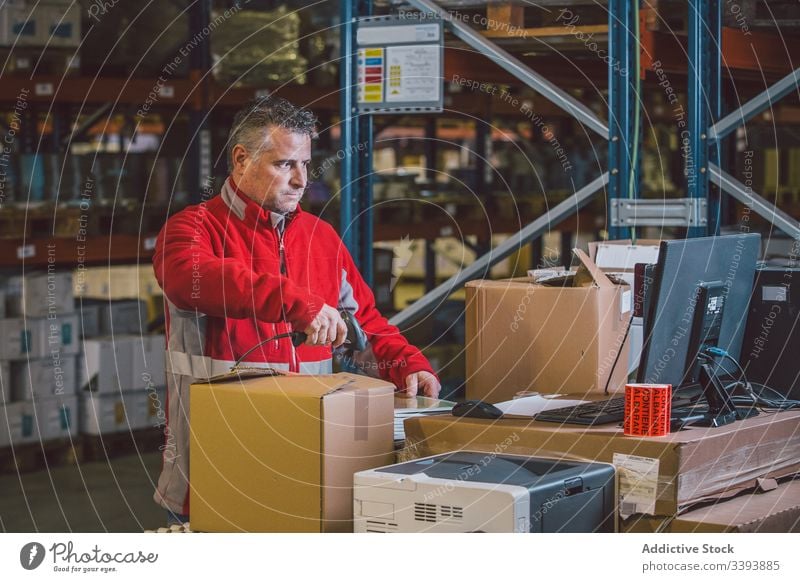 Man scanning packages while working in warehouse logistic service storage male man box job delivery shipment industry professional purchase modern order parcel