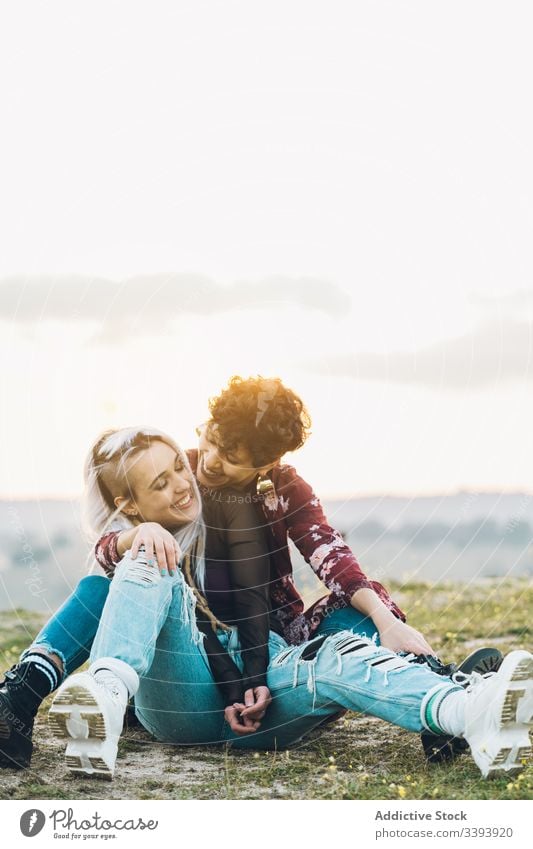 Content female teenagers hugging on grass women girlfriend laugh fun nature meadow best friend embrace smile enjoy share casual contemporary sit hipster green