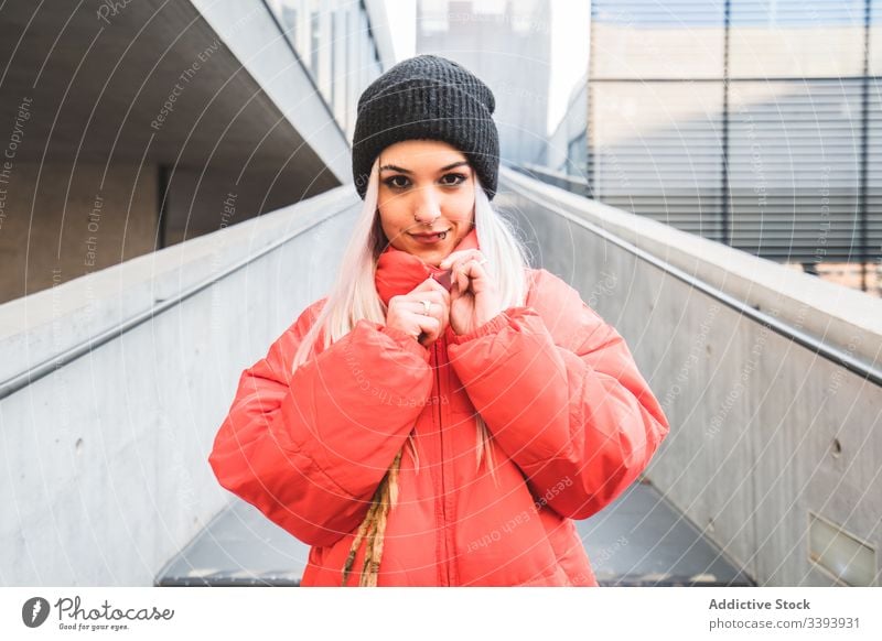 Contemporary woman in trendy warm coat on city street warm clothes hipster blond modern casual style urban stair hat lifestyle architecture young town