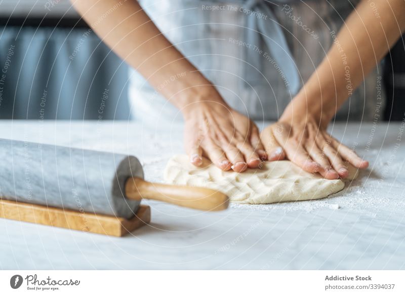 Cook kneading dough with hand on table cook rolling pin flour preparation bakery kitchen culinary making apron recipe food homemade prepare raw cuisine