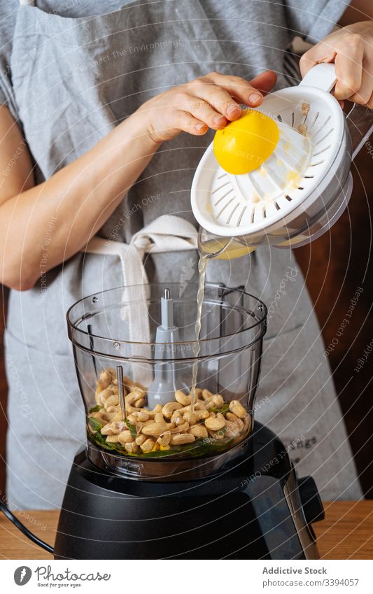 Crop lady adding lemon juice into blender woman cook spill juicer cashew kitchen vegan healthy dish kitchenware appliance food preparation home meal diet