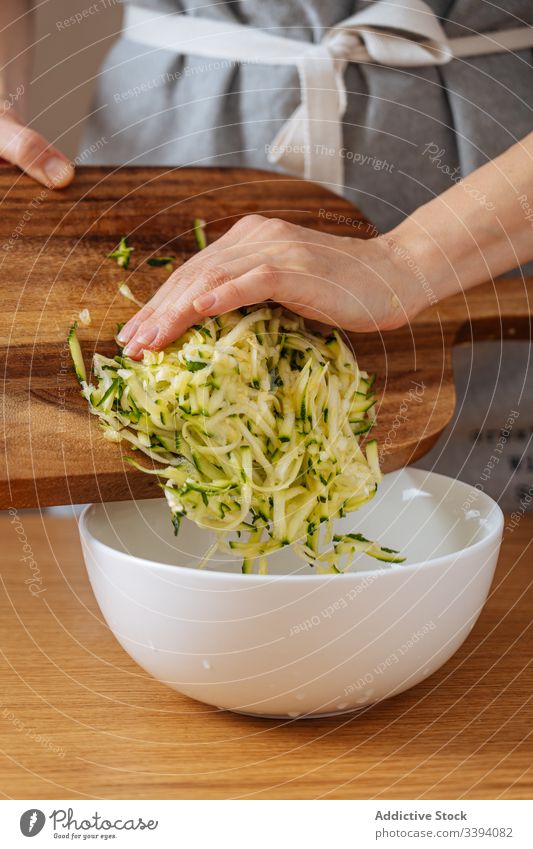 Woman putting grating zucchini into bowl cooking food woman recipe vegetable ingredient kitchen healthy meal female housewife dinner lunch homemade preparation