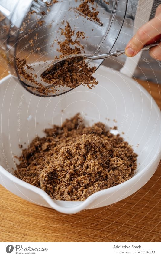 Woman putting ground ingredient into bowl food cooking grind processor recipe kitchen preparation brown lentil healthy bean seed meal female housewife dinner
