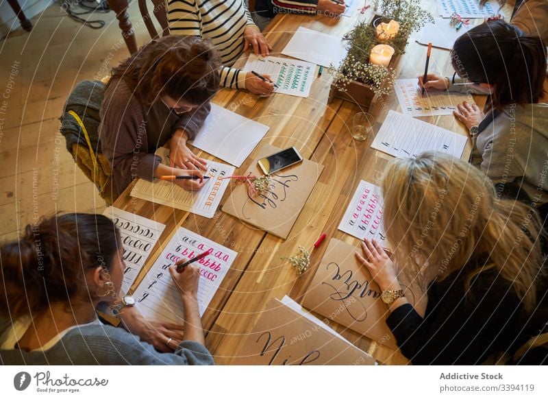Lettering lesson in art studio draw students coach table group meeting casual lifestyle gather creative colleague cooperate collaborate interact project
