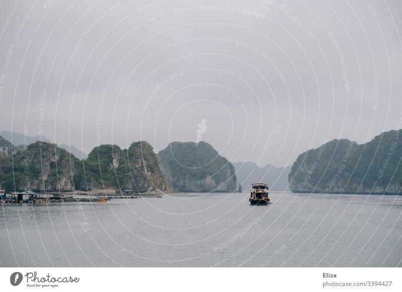 An excursion boat in Halong Bay in Vietnam; beautiful landscape with limestone rocks rising out of the sea in foggy weather Halong bay Ocean Limestone rocks