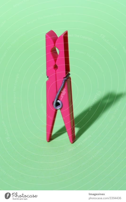 Clothespin - pink coloured plastic clothespin on green background. Minimalist concept art. Abstraction. Shadows. Coloured clothespin insulated Pink