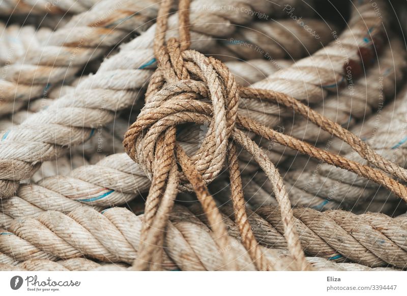 Close-up of thick, rough ropes and cables in beige and one knot