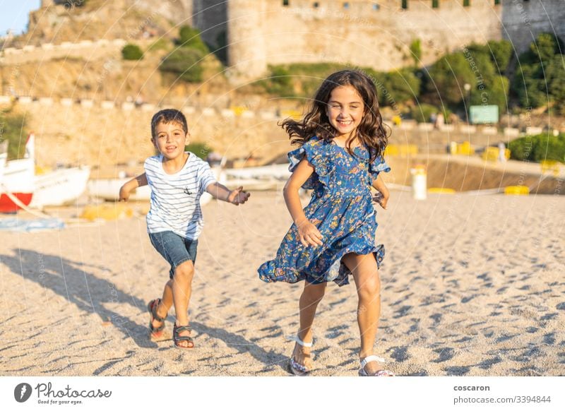 Two little friends running on the beach action active beautiful blue boys cheerful child childhood children colourful competition concept cute friendship fun
