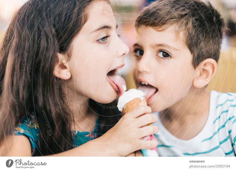 Two little kids eating an ice cream together beautiful boy cafe caucasian cheerful child childhood children close up cute delicious dessert emotion enjoy