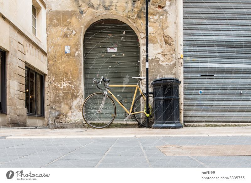 Still life of an old town facade with racing bike trash can and closed rolling gate Old town Building Broken Wall (barrier) Roller shutter Racing cycle