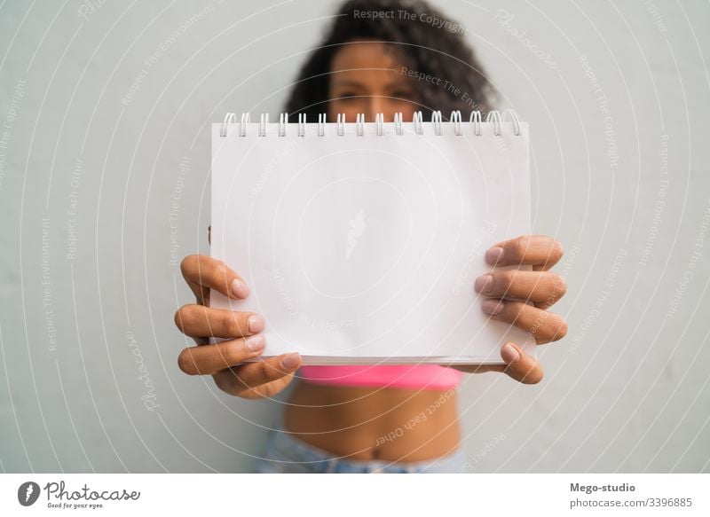 Young afro woman holding blank paper. empty happy showing copyspace presenting advertise introducing showing product content demonstration blank sign young look