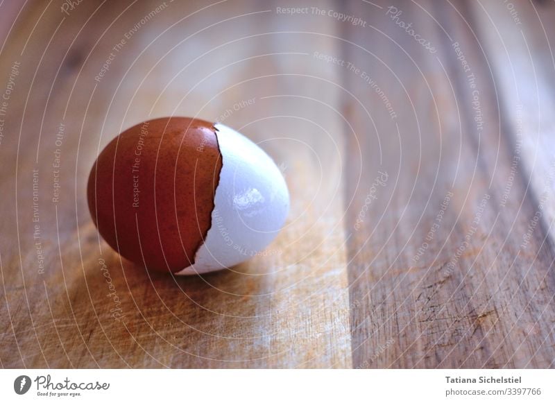 egg lying on a wooden board with a brown shell, which has a white shell as a cap Egg Brown Eggshell Easter Brownish white Breakfast Nutrition peel Wooden board
