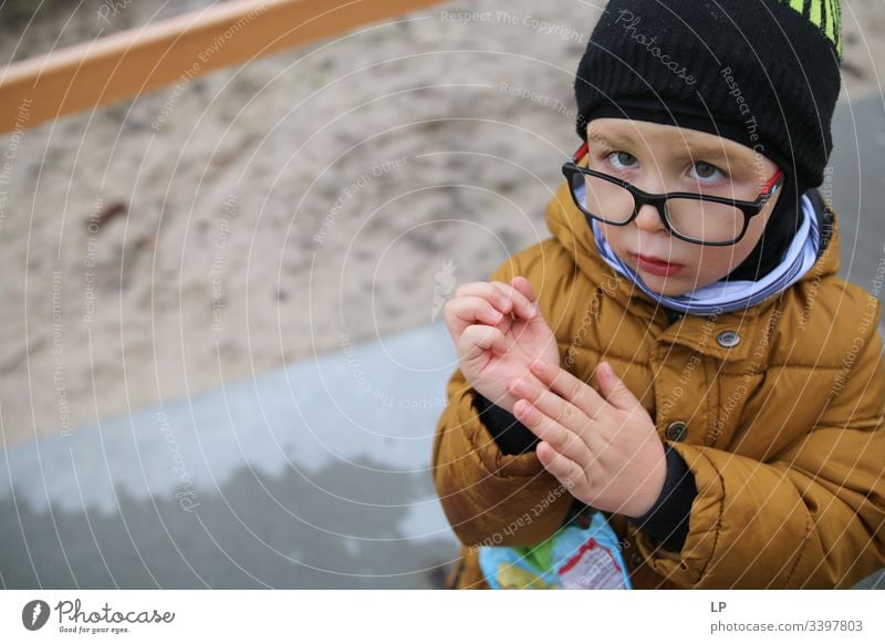 Boy looking into the camera showing his hand Looking into the camera Observe curious down Curiosity Eyes Children's game Childhood memory Childhood wish