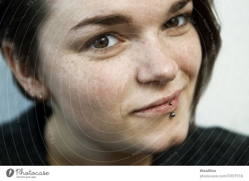Portrait of a young woman with lip piercing and freckles Forward Portrait photograph Central perspective Shallow depth of field Day Close-up Interior shot