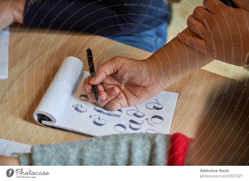 Faceless woman learning lettering at table draw paper handwriting occupation desk workplace art creative craft graphic education notebook skill stationery