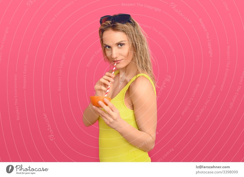 Woman drinking through a straw from an orange attractive beautiful cellulite treatment cheerful cocktail colorful concept conceptual delicious diet expression