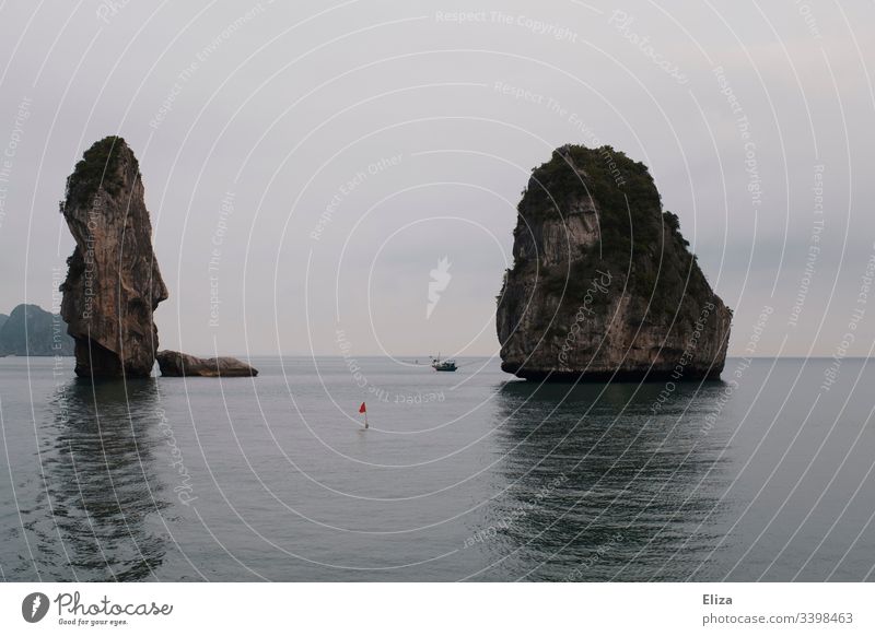 Towering limestone cliffs in Halon Bay in Vietnam Limestone rocks Halong bay Ocean Tall Landscape Nature Water Asia Tourist Attraction Dreary somber cloudy