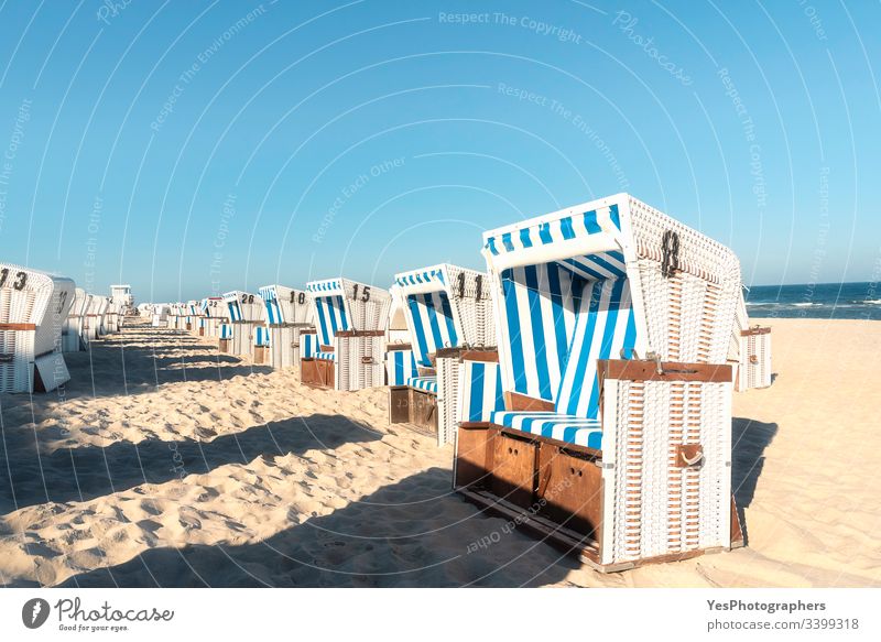 Beach chairs in a row on Sylt island. Sea beach on sunny day Frisian island Schleswig-Holstein Wadden sea aligned beach chairs blue sky coastline dunes