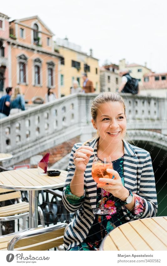 Young female traveler enjoying a glass of spritz in an outdoor cafe in Venice, Italy adult alcohol aperitif aperol beverage bridge caucasian cheerful city