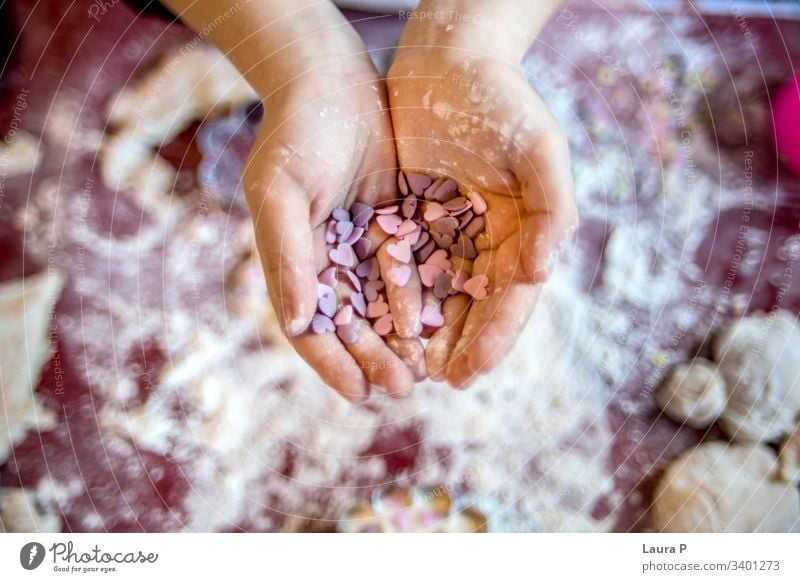 Child little hands holding heart shaped sweets child hearts Heart-shaped Love Colour photo pink purple cooking baking flour fingers desert Close-up