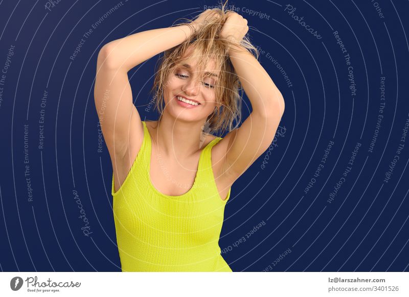 Happy carefree blond woman with hands to hair active adolescent background blue camera colorful copy cute energetic exercise fashion fitness glamour grinning