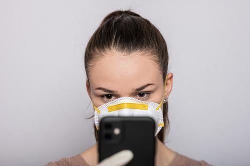 Woman with a mouthguard and disposable gloves types on her mobile coronavirus covid-19 Virus Illness pandemic Epidemic Mask guard sb./sth. hand protection