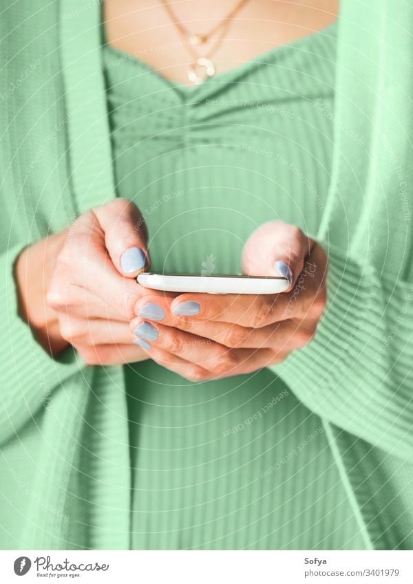 Woman using white smartphone. Mint green color of 2020 woman green mint neo color year hands screen mobile device internet connection communication nature light
