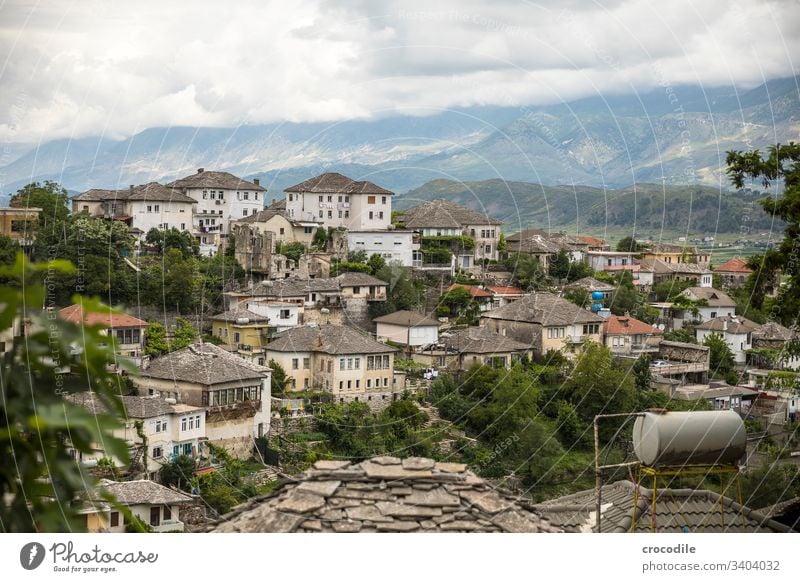 View of the old town of Gjirokaster, Albania Old town Historic Housefront Town Balkans Mountain UNESCO World Heritage Site Clouds roofs Water tank