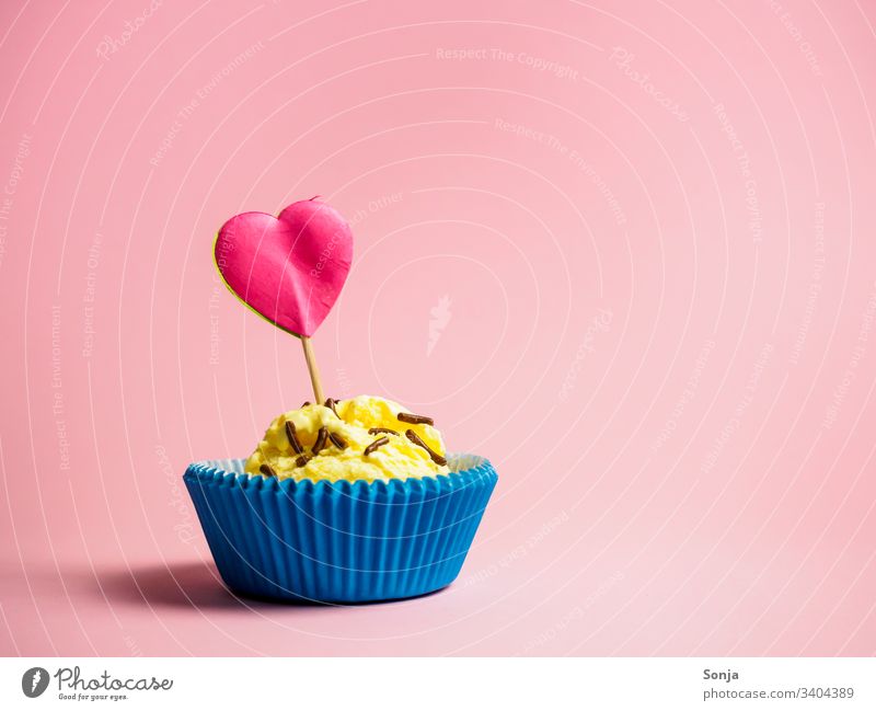 Vanilleeis in einer blauen Muffinform mit einem pinken Herzen auf einem rosa Hintergrund vanilleeis muffinform herz papier Colour photo Summer liebe geburtstag