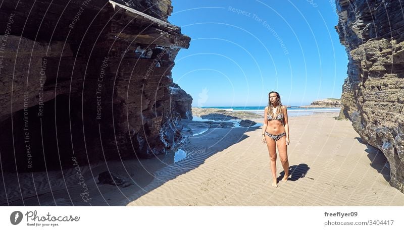 Young woman walking by a beach with cliffs in Galicia, Spain tourism hiking galicia spain ribadeo castros illas rock atlantic bay touristic cathedrals ocean
