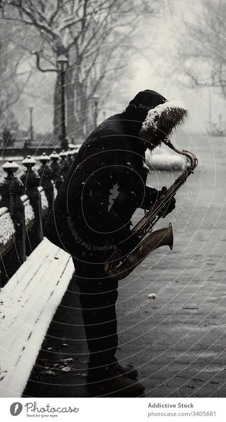 Anonymous man with saxophone at city street play winter modern jacket music melody sound instrument male entertain lifestyle season new york park harmony