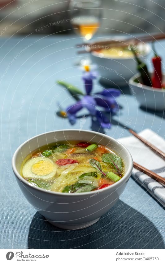 Oriental noodles soup in a restaurant food ramen asian chinese white vegan food vegetables vegetarian healthy food egg carrots onion spinach shiitake background