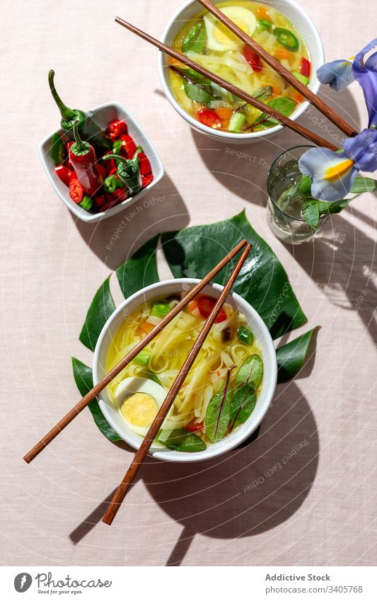 Oriental noodles soup in a restaurant food ramen asian chinese white vegan food vegetables vegetarian healthy food egg carrots onion spinach shiitake background