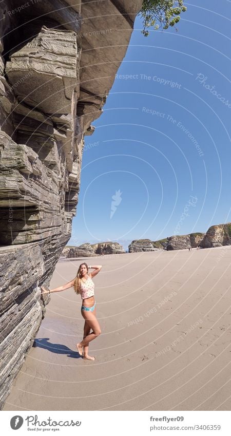 Young woman scaling herself with a cliff on a beach tourism hiking galicia spain ribadeo castros illas rock atlantic bay touristic cathedrals ocean travel