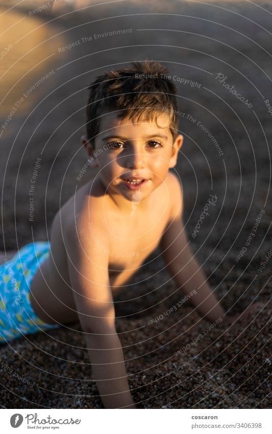 Portrait of little boy lying down on the sand beach beach holiday beautiful carefree caucasian child childhood coast copy space cute face freedom fun happiness