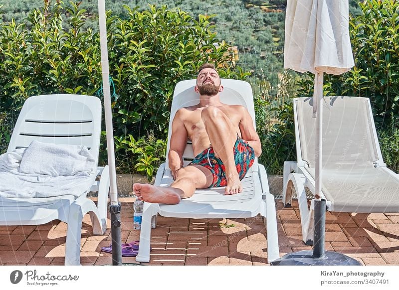Handsome bearded man sunbathing on lounge chair enjoying with summertime leisure tan male person sunny caucasian rest recreation pool lying swimwear tourism guy
