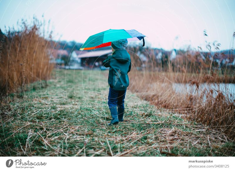 Boy with colorful umbrella Boy (child) variegated Umbrella Weather protection Rainy weather explorers Discover Rubber boots
