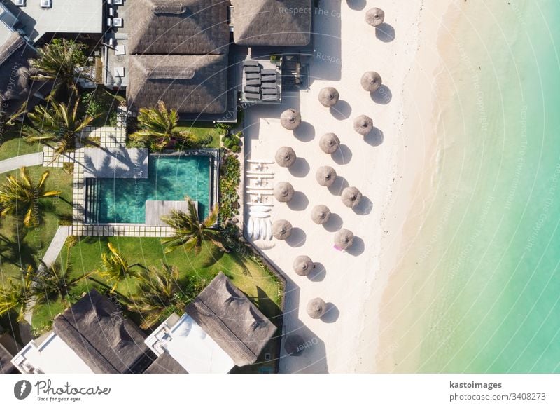 Aerial view of amazing tropical white sandy beach with palm leaves umbrellas and turquoise sea, Mauritius. beachfront resort travel pool hotel blue summer water