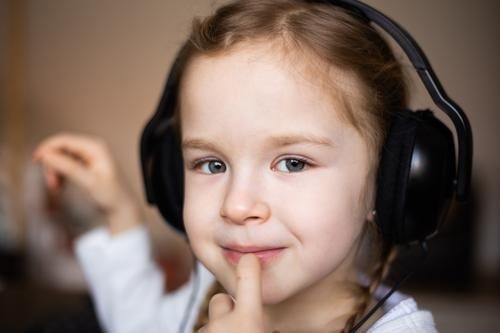 Close up of a beautiful blonde little girl listening to music at headphones smile happy young beauty child kid daughter fun cute enjoy isolated person