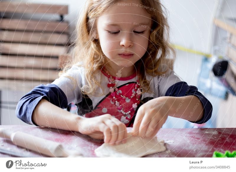 Beautiful blonde little girl playing with dough beautiful curly hair cooking baking table doughtnuts Baked goods Dough Baking Colour photo Flour Food home made