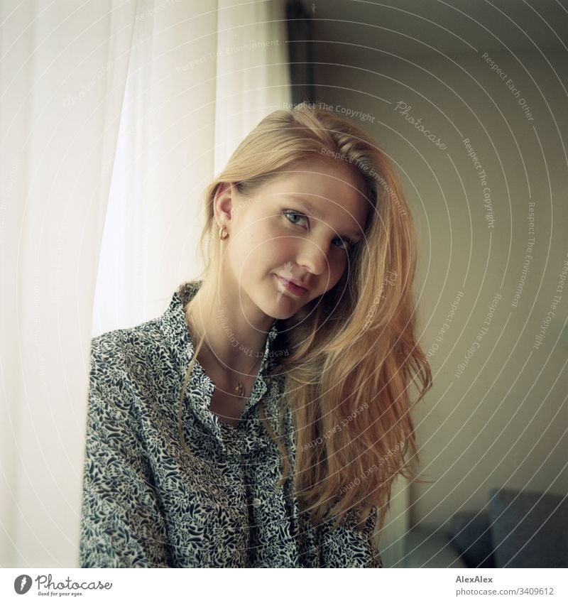 Portrait of a young woman beside the window at the curtain Woman Girl Blonde Beautiful youthful Slim daintily Elegant Lifestyle dwell Flat (apartment) at home