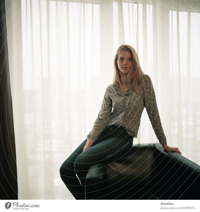 Portrait of a young woman on an armchair in front of the window Woman Girl Blonde Beautiful youthful Slim daintily Elegant Lifestyle dwell Flat (apartment)