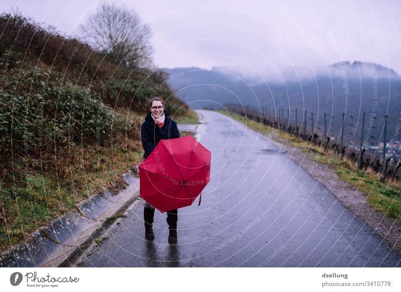 Rain walk of a young woman with a red umbrella rainy day Umbrella Wet Bad weather Colour photo Exterior shot Weather Smiling Umbrellas & Shades Fog Protection