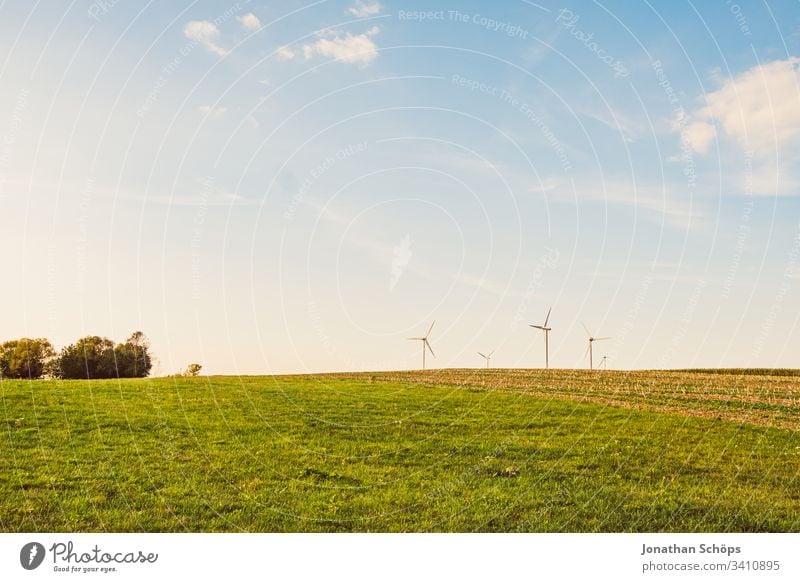 ecological renewable green energy wind power station on a field in evening sun alternative background blue change clean climate change cloud clouds countryside