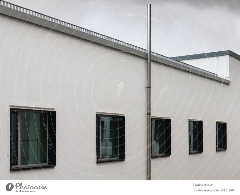 White facade with black windows in front of a grey sky Facade House (Residential Structure) Window Black Gray fenter frame Perspective conduit Stone Building